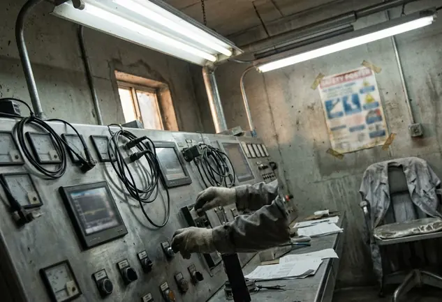 Control panel with gauges and readouts, industrial setting illuminated by harsh, uneven fluorescent lab lights